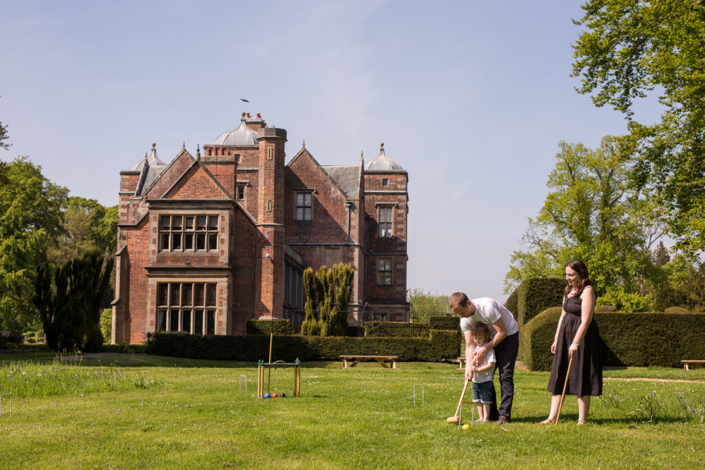 Family playing croquet on the lawn in front of Kiplin Hall